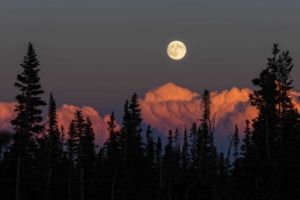 Harvest Moon. The full moon, a September fall harvest moon, rises above billowing cumulus clouds glowing orange illuminated by the sunset. The full moon, a September fall harvest moon, rises above billowing cumulus clouds glowing orange illuminated by the sunset