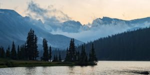 Tranquility. Landscape photograph of dusk blue mountains of Indian Peaks Wilderness becoming enshrouded in clouds under smoky orange sky taken from the shore of Long Lake Boulder County Colorado. <a href="https://www.etsy.com/listing/608942329/tranquility-fine-art-landscape?ref=shop_home_active_20"_blank" rel="nofollow noopener noreferrer">Purchase at Etsy</a> Landscape photograph of dusk blue mountains of Indian Peaks Wilderness becoming enshrouded in clouds under smoky orange sky taken from the shore of Long Lake Boulder County Colorado