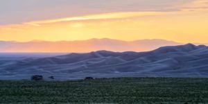 Desert Solace. Pastel orange and blue themed landscape photograph of a tranquil sunset over Great Sand Dunes National Monument in the San Luis Valley Colorado. Pastel orange and blue themed landscape photograph of a tranquil sunset over Great Sand Dunes National Monument in the San Luis Valley Colorado